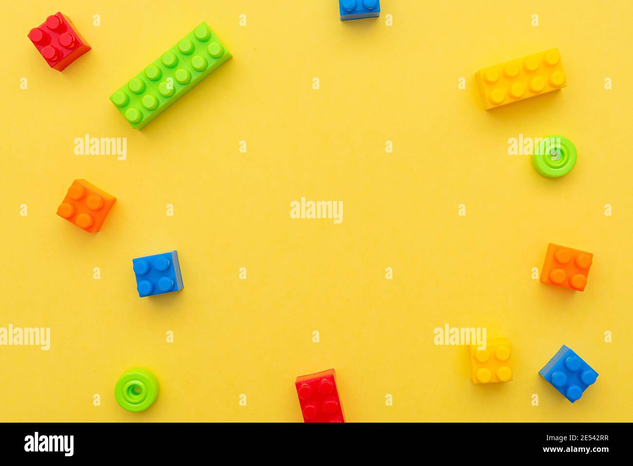 Small blocks of plastic constructor on yellow background, flat lay, top view, space for text Stock Photo