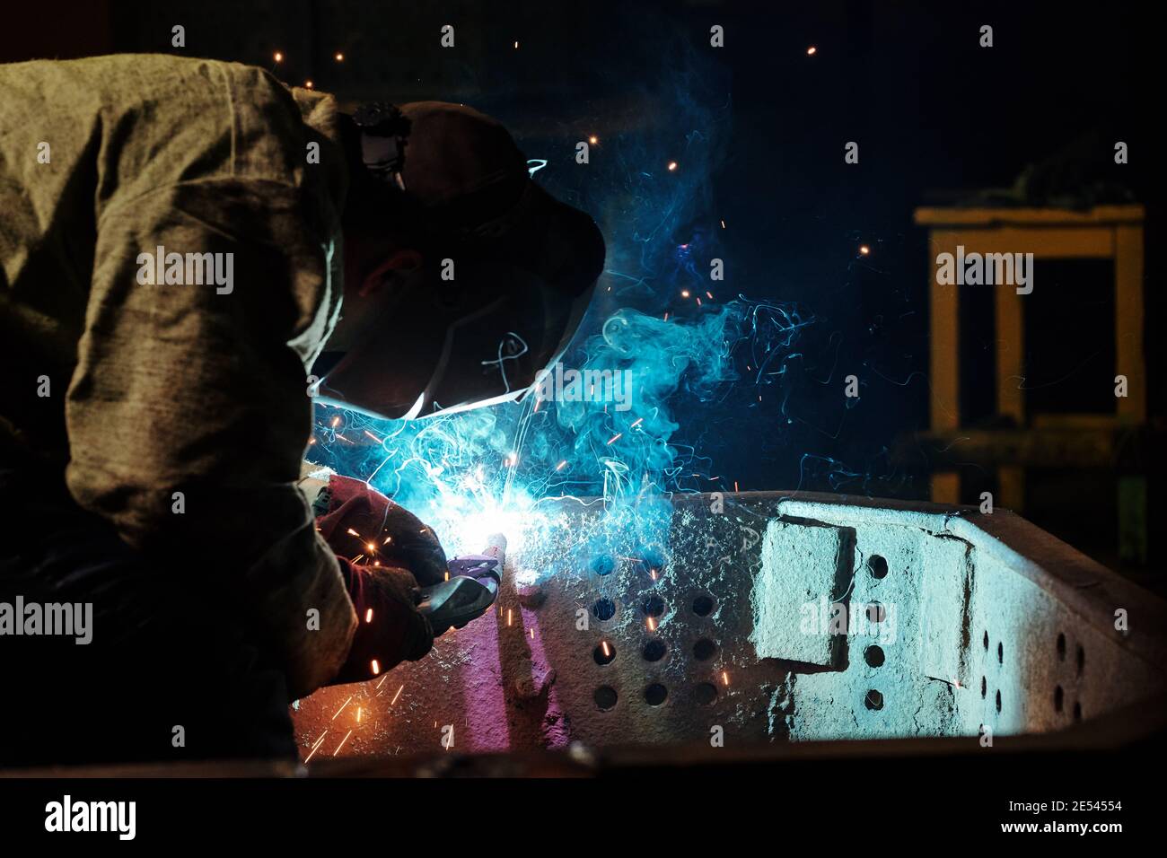 Worker in protective mask using angle grinder in workshop Stock Photo