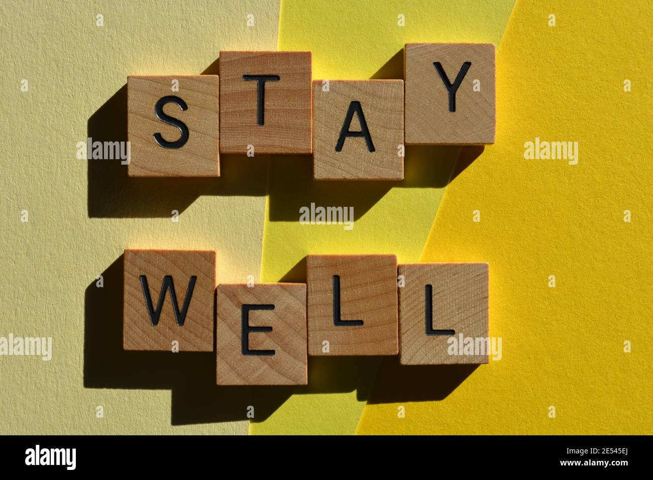Stay Well, words in wooden alphabet letters isolated on yellow background Stock Photo