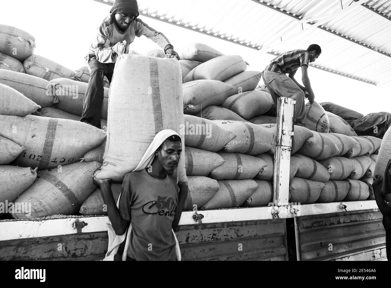 ADDIS ABABA, ETHIOPIA - Jan 05, 2021: Addis Ababa, Ethiopia - January 30 2014: Men stacking large bags of coffee beans in a warehouse Stock Photo