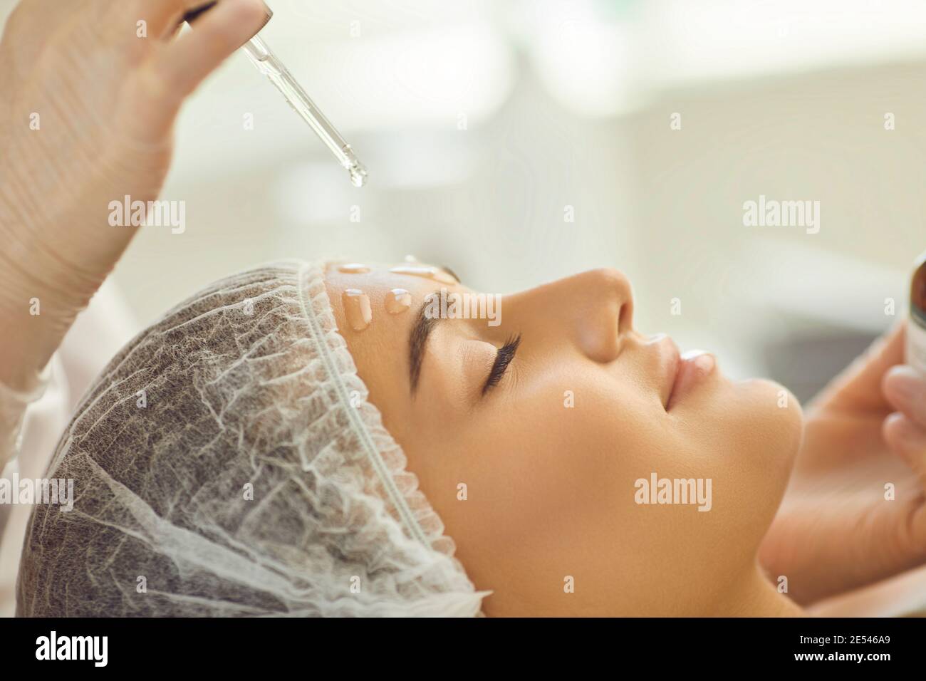Smiling womans face getting skincare procedure of applying nourishing oil on skin Stock Photo