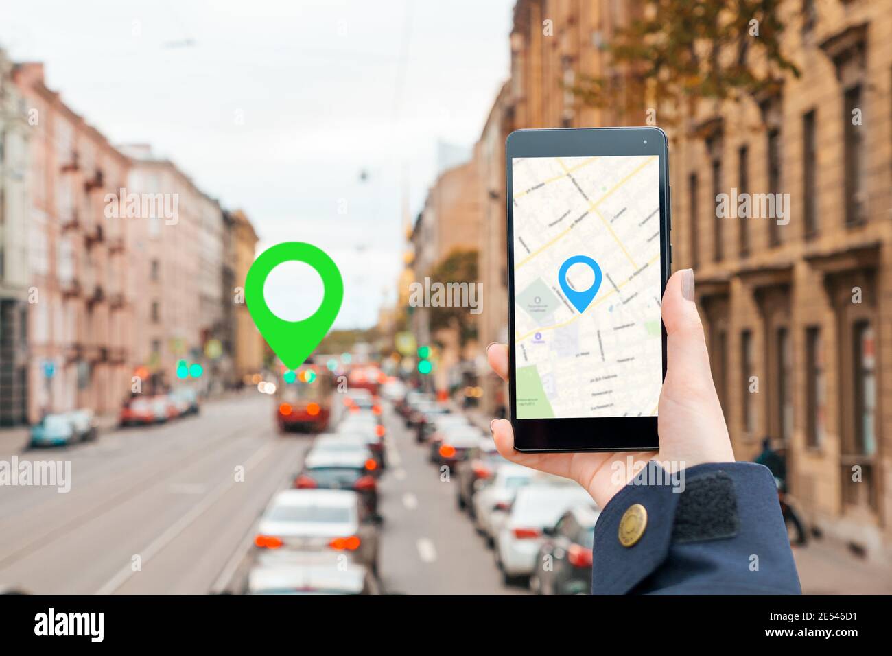 A woman's hand in a jacket holds a smartphone with an online map app ...