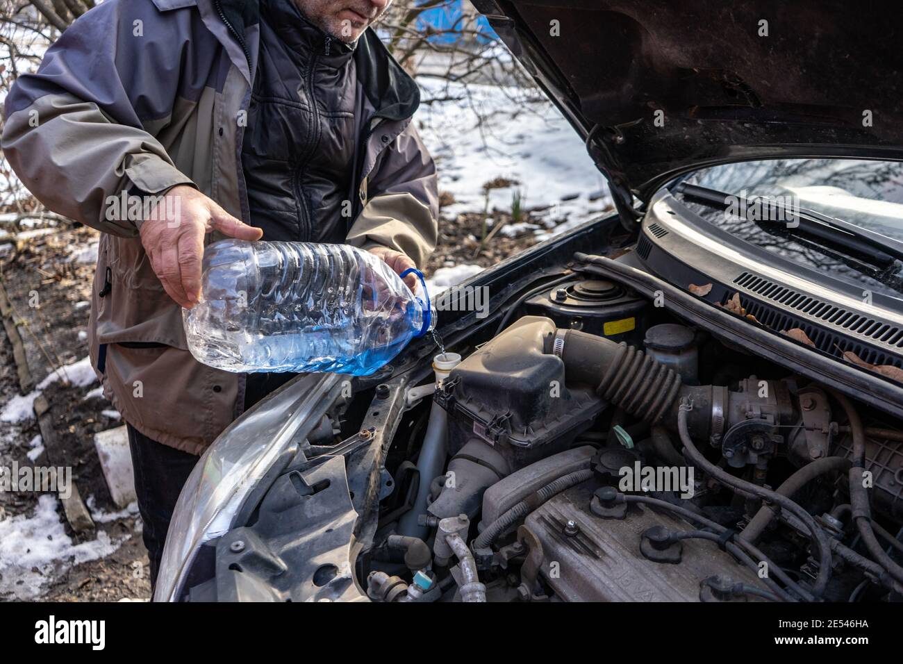 man pouring antifreeze into special fluid tank Stock Photo