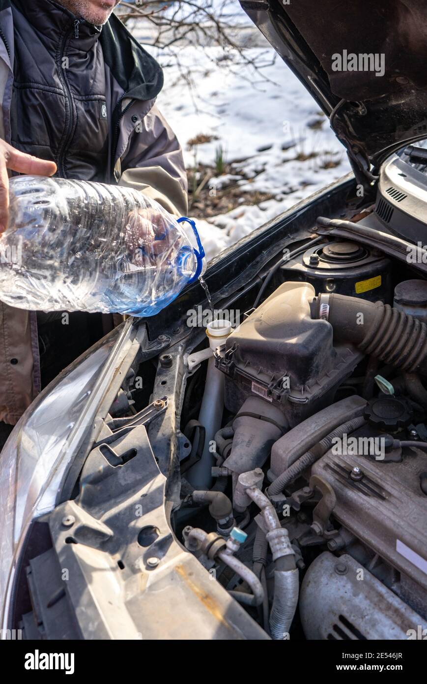 man pouring antifreeze into special fluid tank Stock Photo