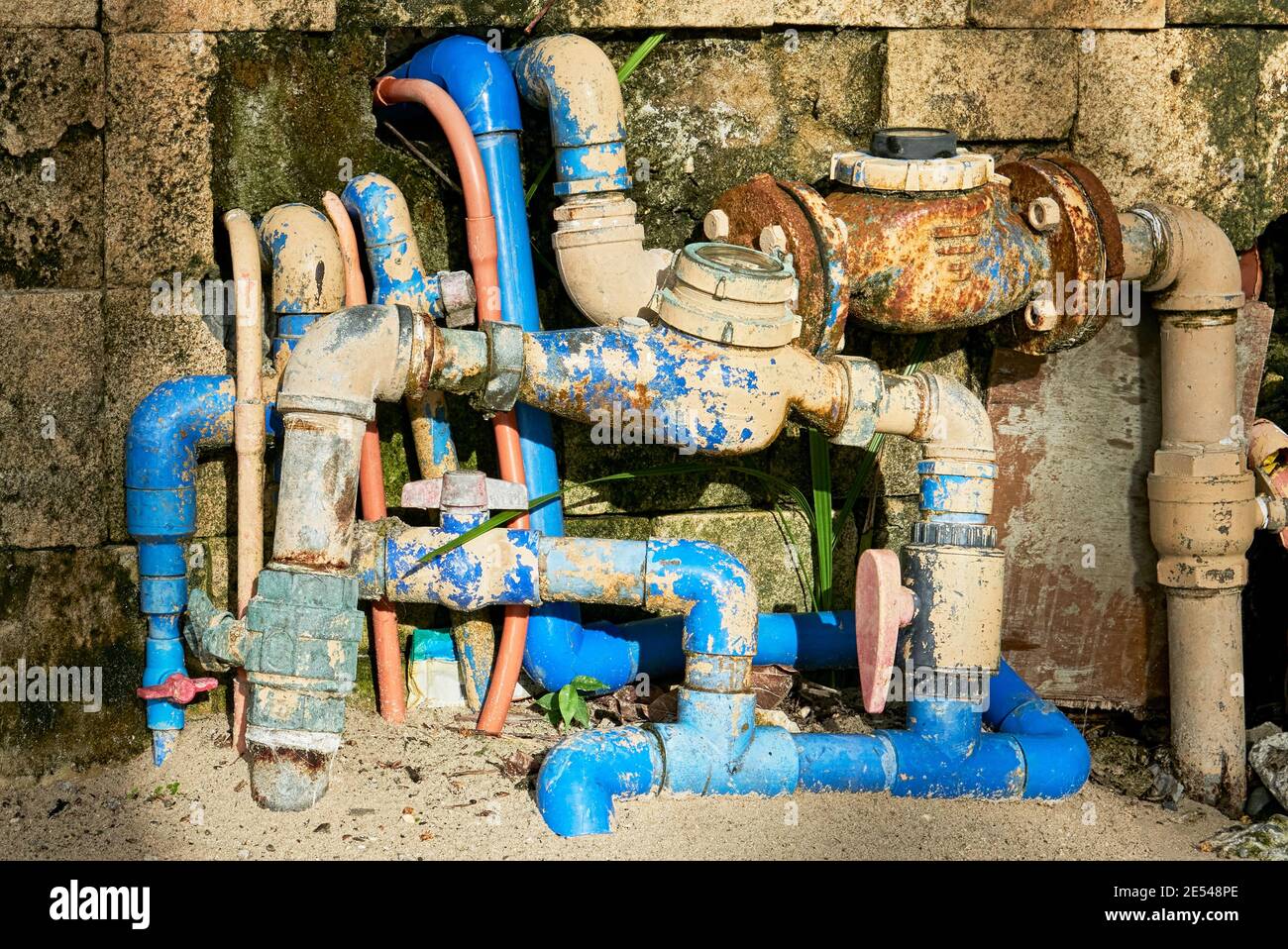 Confusing detail of rusty water meters, valves and blue pvc pipes outside  of a dirty house wall Stock Photo - Alamy