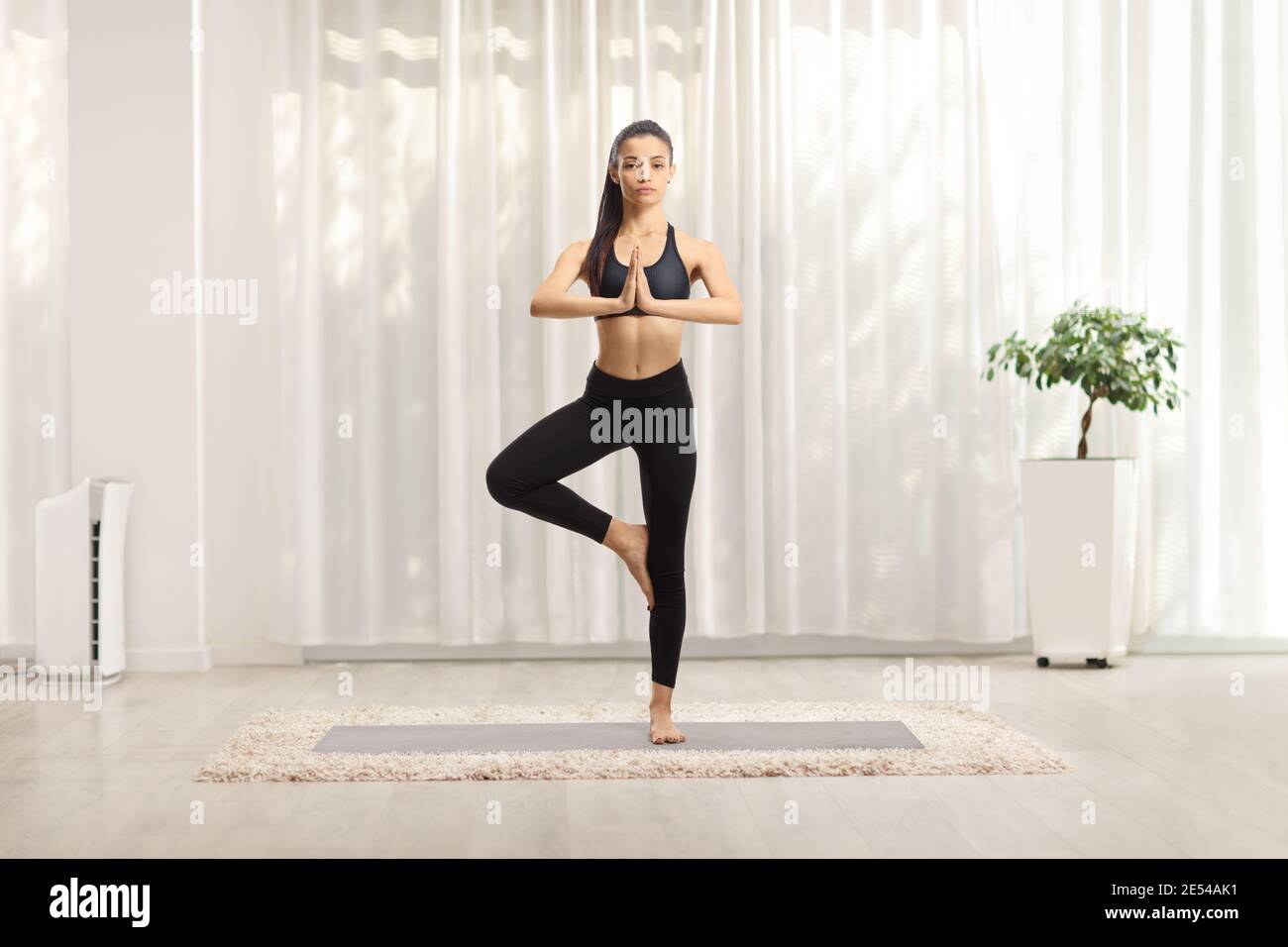 Full length portrait of a young female exercising a yoga pose on a mat ...