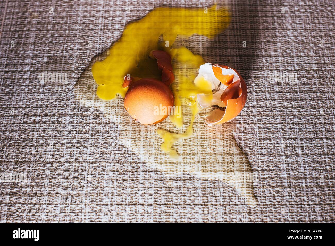 Broken egg on the floor on the tile the egg shell and yolk spilled as