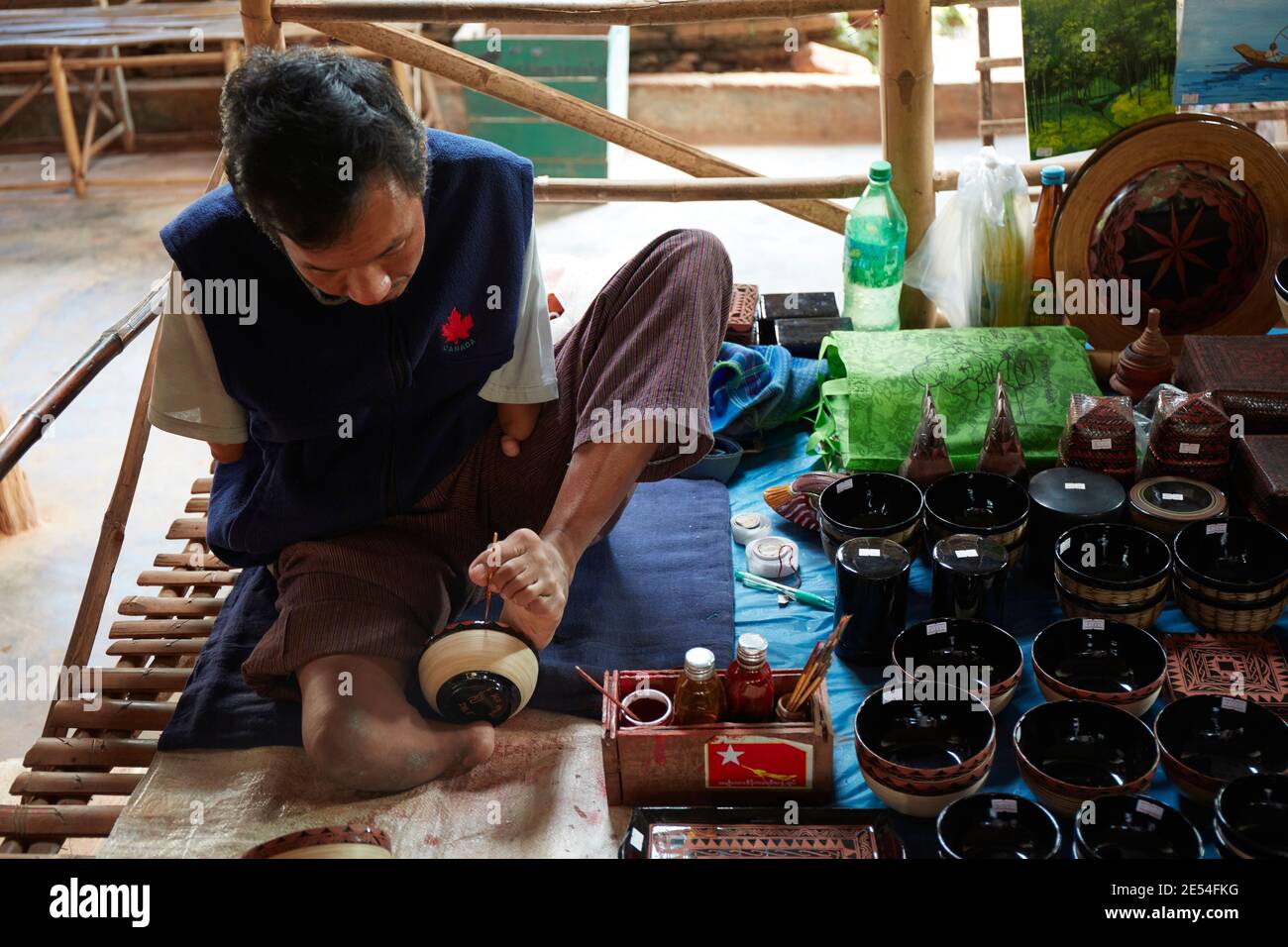 A Burmese craftsman paints a bowl with a foot in a street stall, Inle Lake, Myanmar. Stock Photo