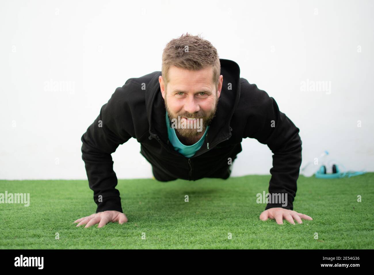 Determined strong young man doing push-ups and looking at camera Stock Photo