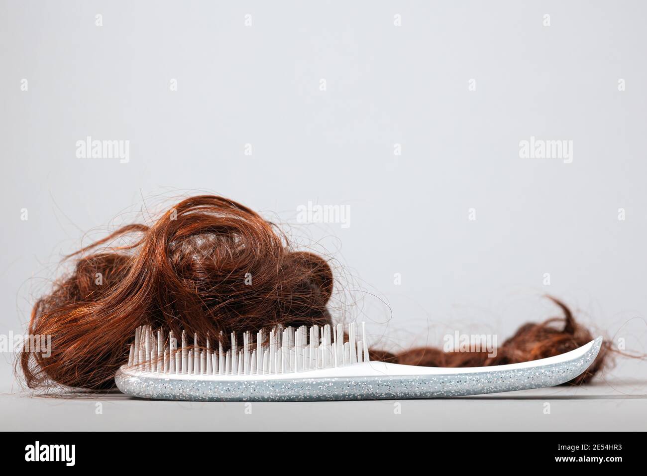 A white comb with false hair. Side view. White background. Copy space. The concept of hair problems and hair care. Stock Photo