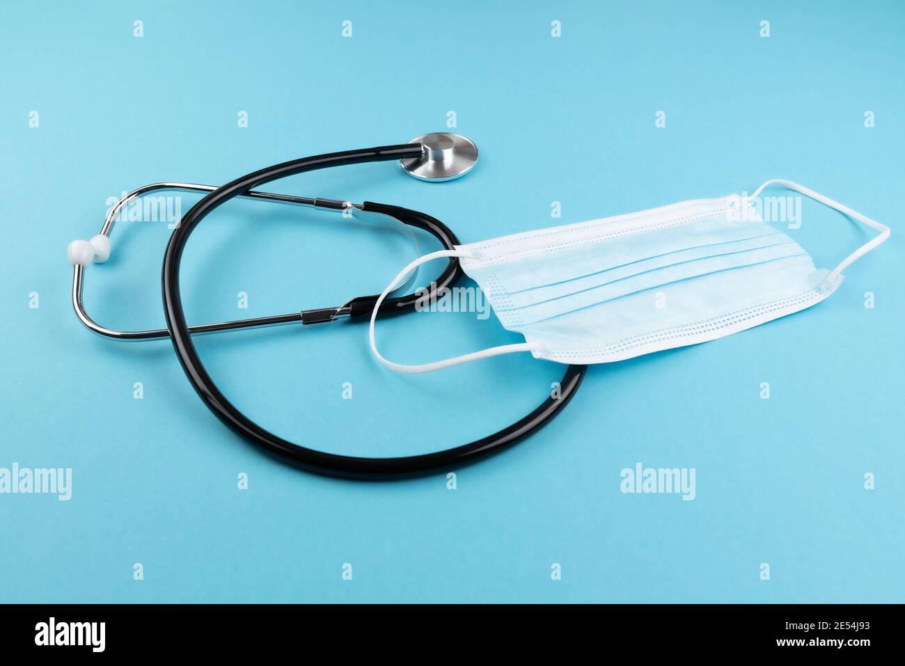 high angle view of stethoscope and surgical mask on blue background, covid-19 coronavirus and respiratory disease concept Stock Photo