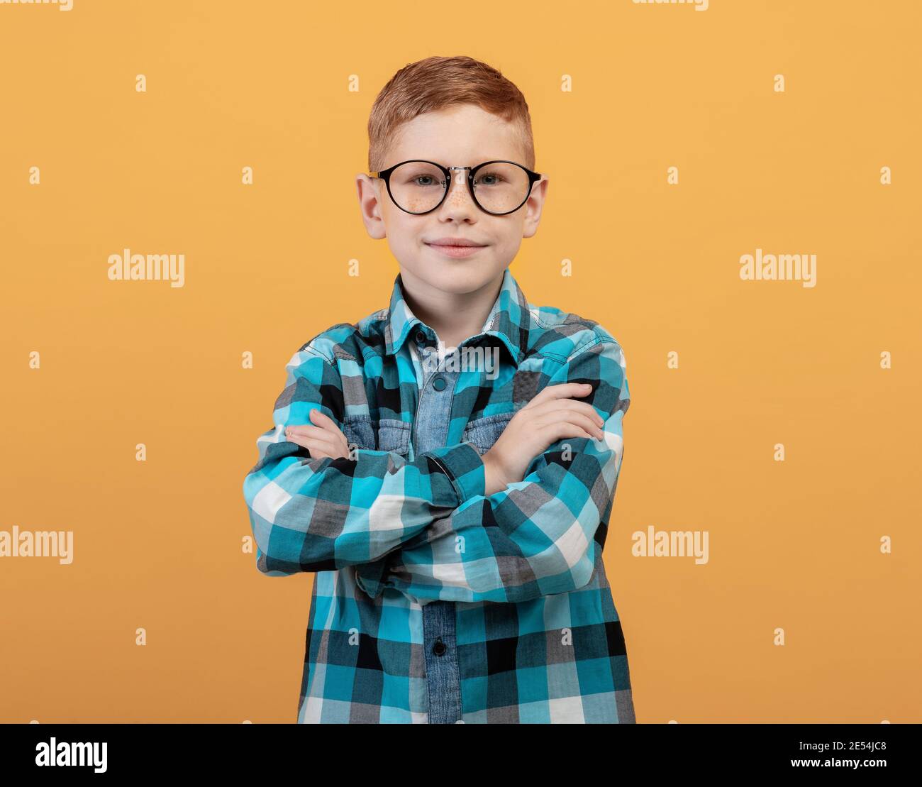 Intelligent ginger boy in glasses posing on yellow Stock Photo