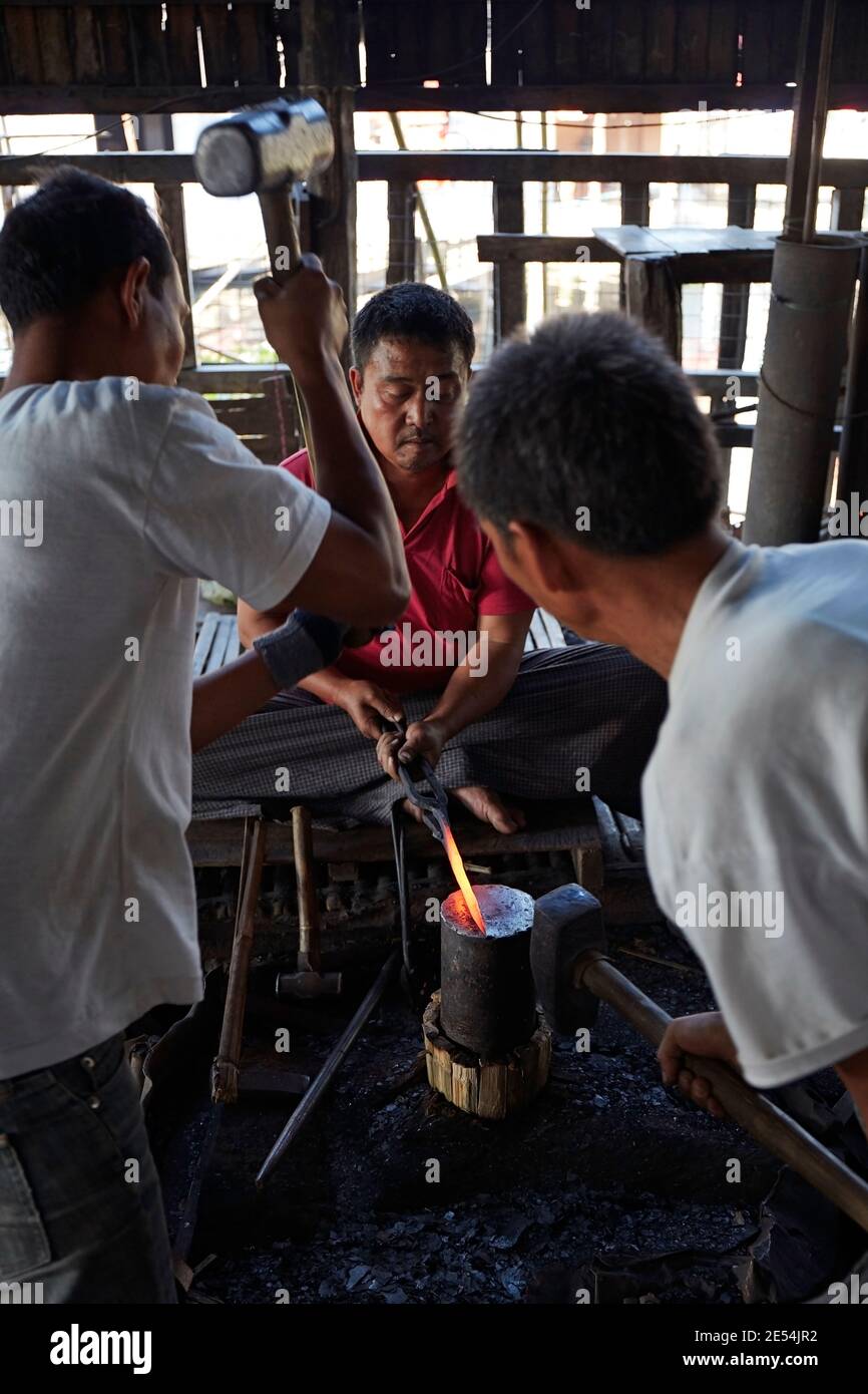 Blacksmiths at work forging iron/steel in a local workshop on Inle Lake, Myanmar. Stock Photo