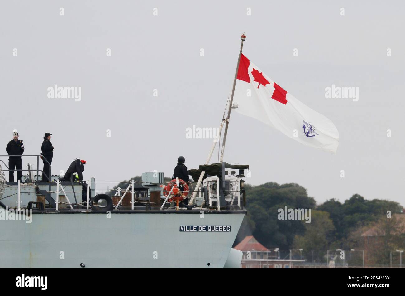 The ensign of the Royal Canadian Navy flies from the stern of the frigate HMCS VILLE DE QUEBEC (FFH332) as the ship leaves harbour Stock Photo