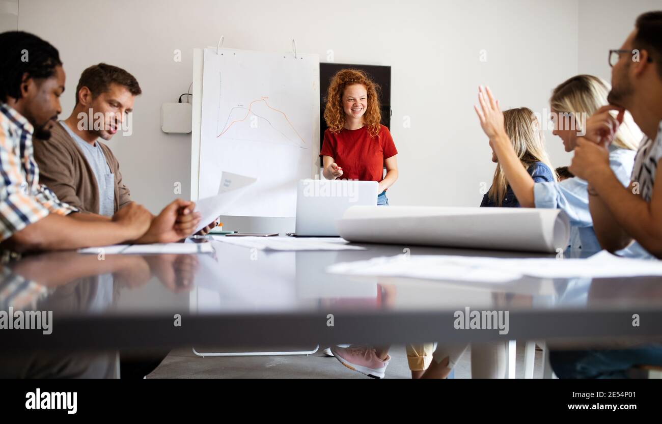 Young architect colleagues are analyzing blueprints while working on a new project Stock Photo