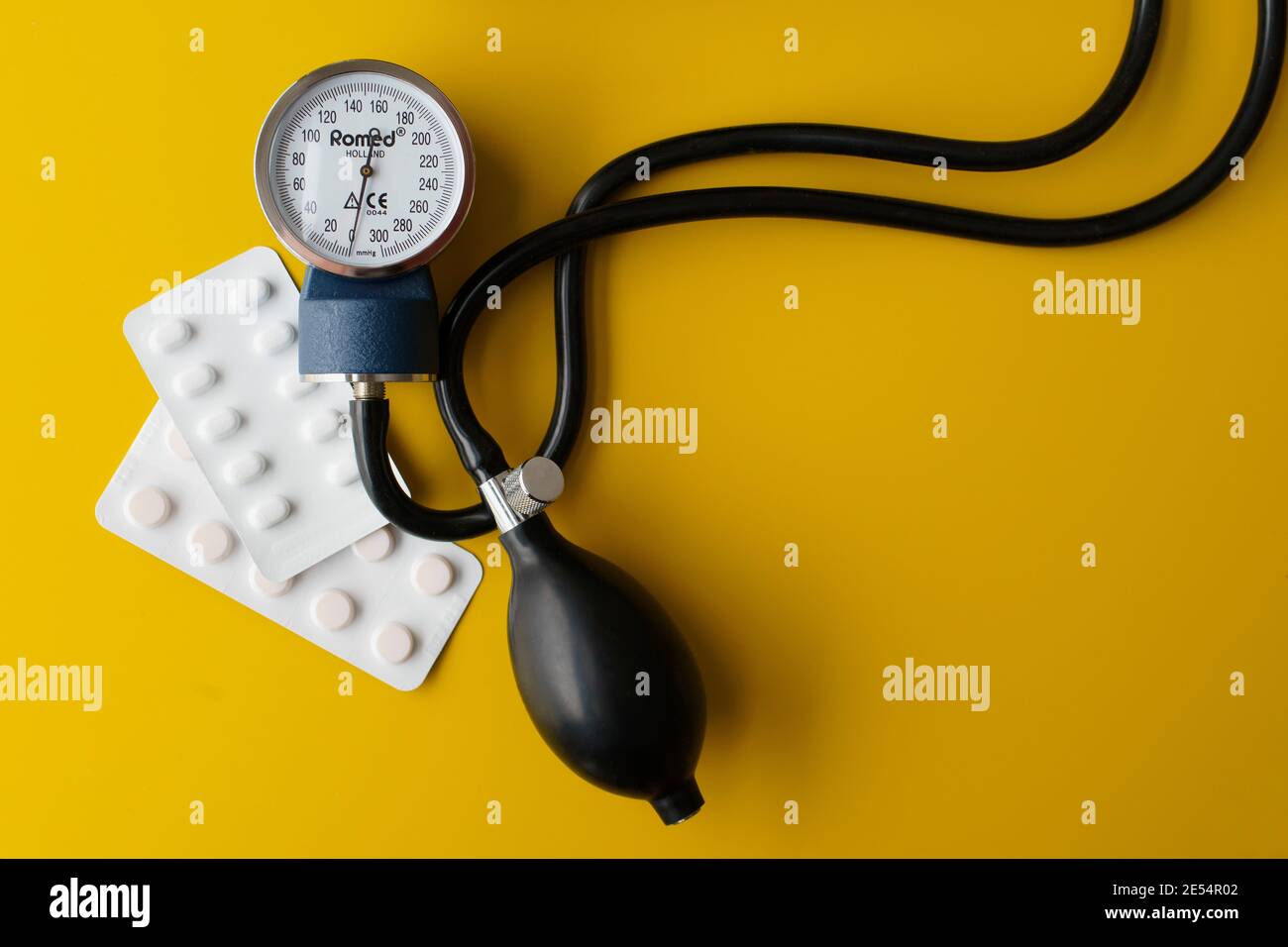 Blood pressure meter with pills on a yellow table Stock Photo