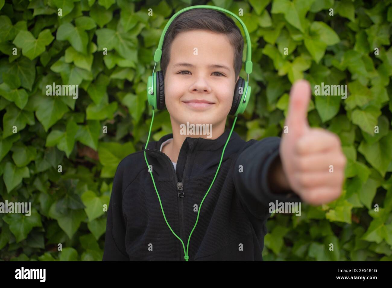 Young smiling boy wearing headphones with thumb up outdoors Stock Photo ...