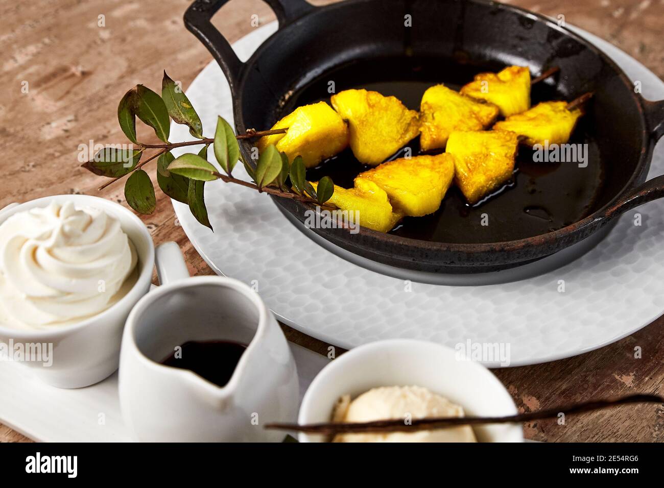 Dessert of pineapple skewer and vanilla flavored ice cream and chocolate Stock Photo