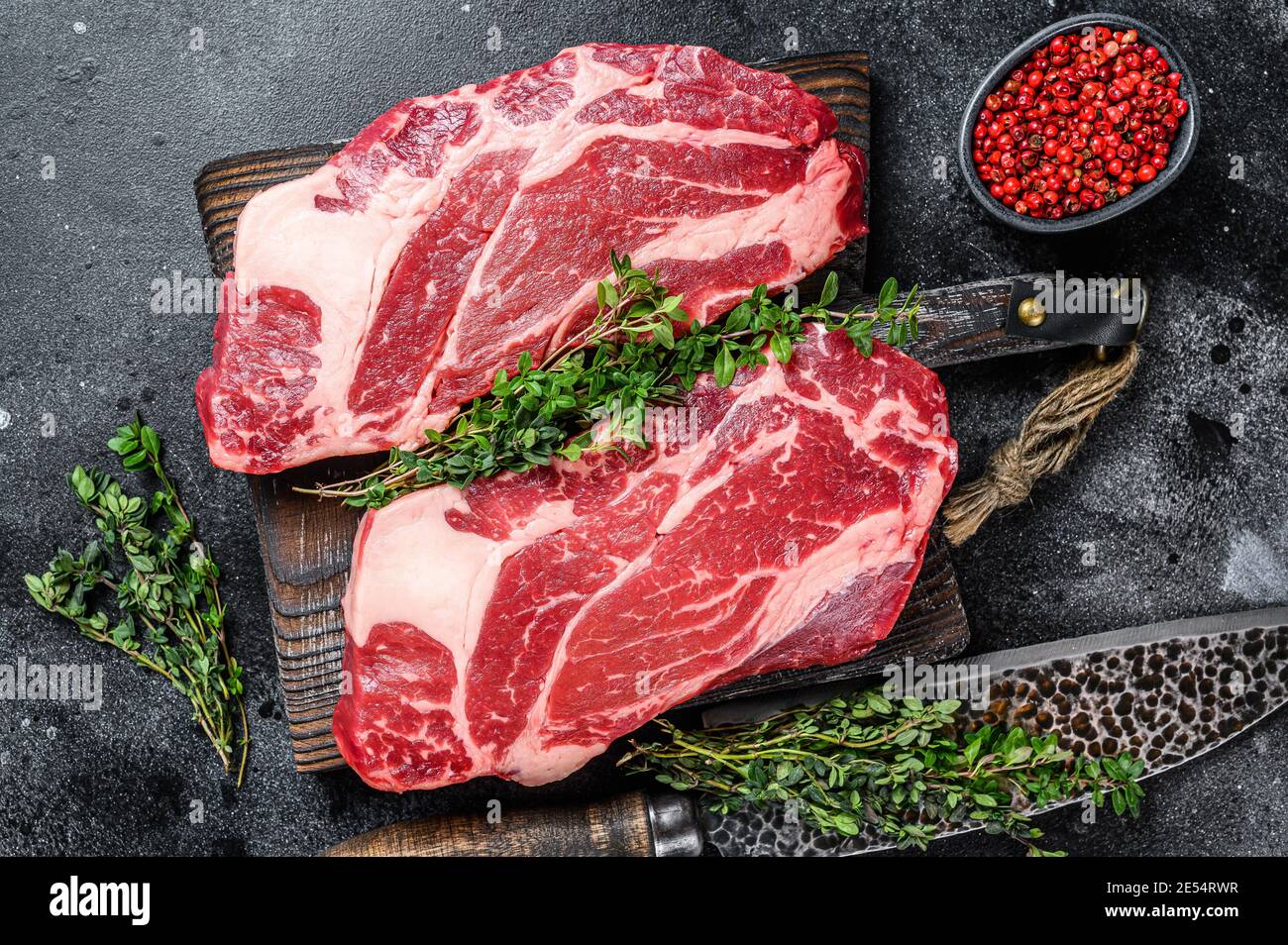 Raw chuck eye roll steaks premium beef meat on a cutting board. Black
