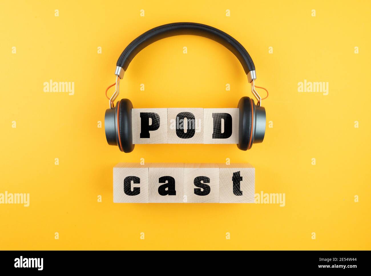 word PODCAST on wooden blocks and headphones on orange background, podcasting concept Stock Photo