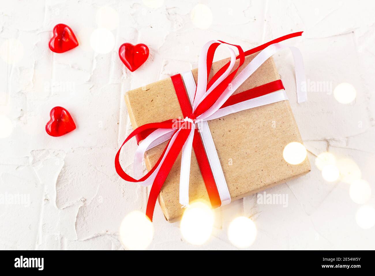 Gift box with red and white bow ribbon and hearts on white table for ...