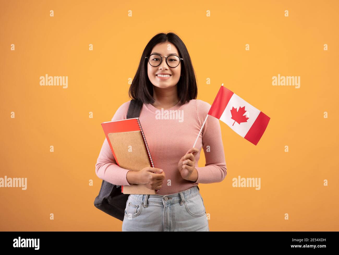 Travel, modern education and student exchange. Young cheerful asian woman in glasses with notebooks Stock Photo