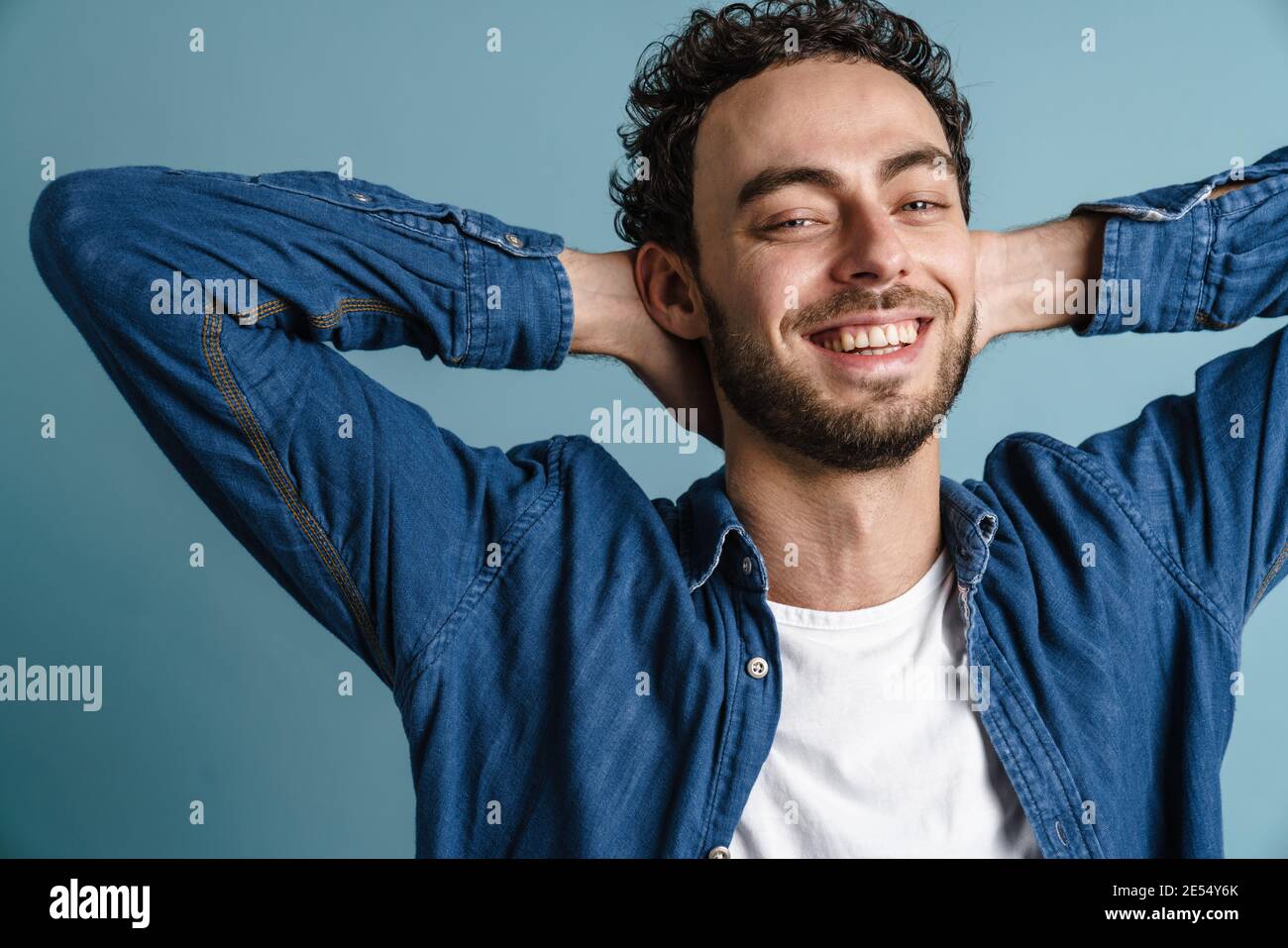 Happy handsome guy posing with hands clasped behind his neck isolated