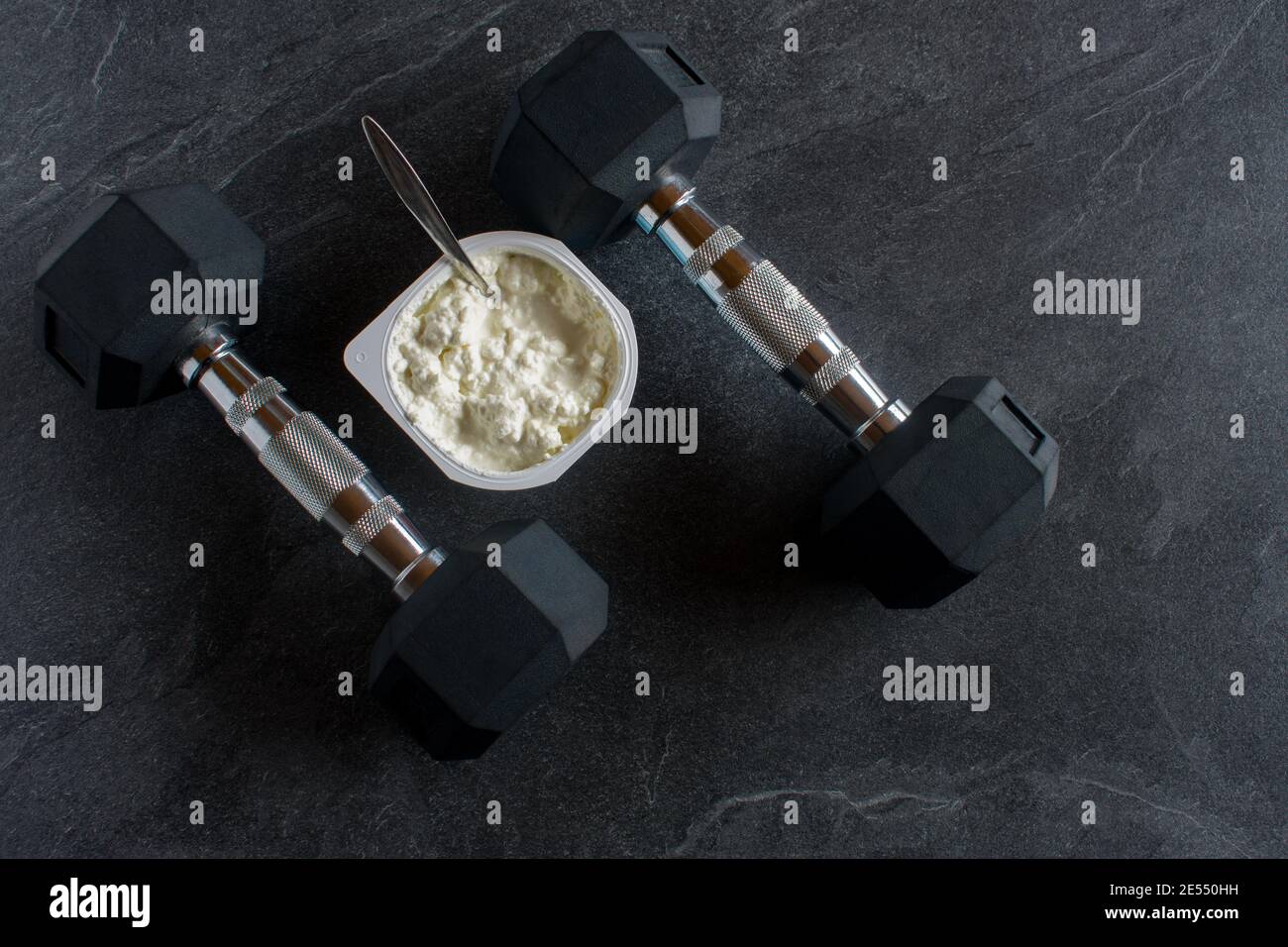 Dumbbells with protein food on dark background from above Stock Photo