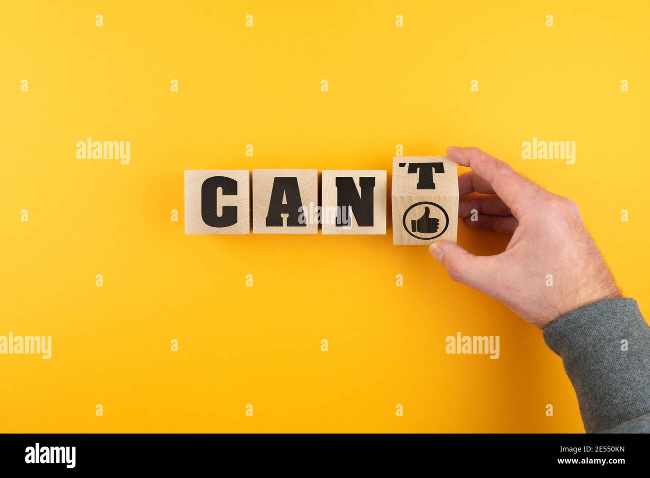 hand changing CANT to CAN on wooden blocks with thumbs up icon against orange background Stock Photo