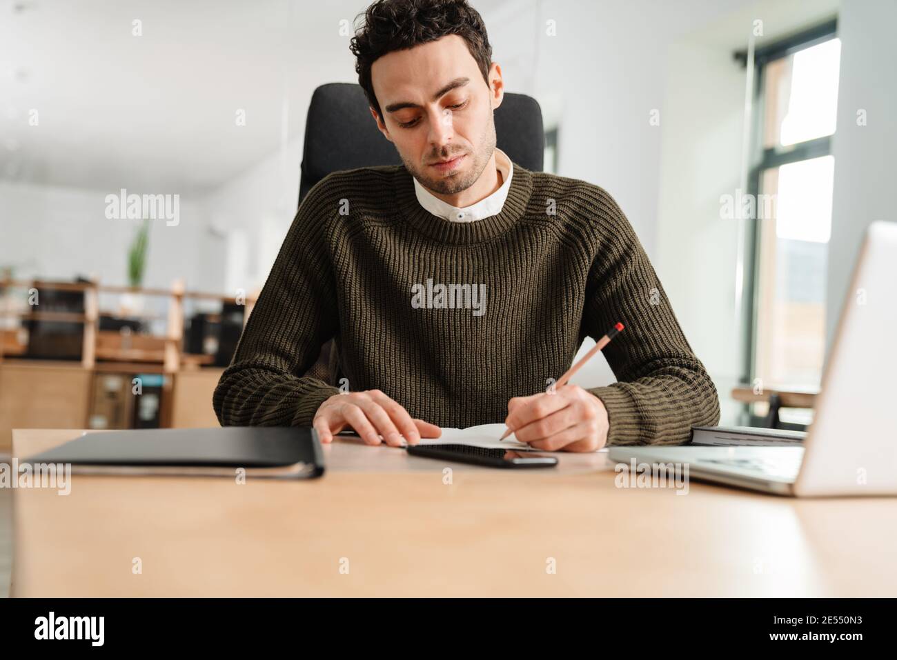 Entrepreneur working with a laptop and documents in an office, taking notes Stock Photo