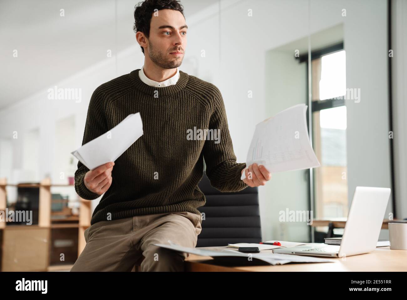Confident young manager working at the office, holding documents Stock Photo