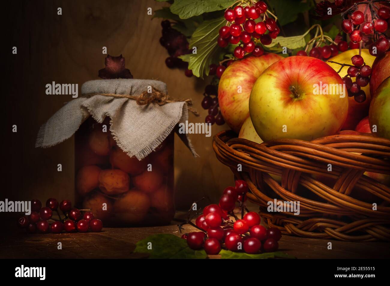 apples and branches of viburnum on a dark wooden background in a rustic ...