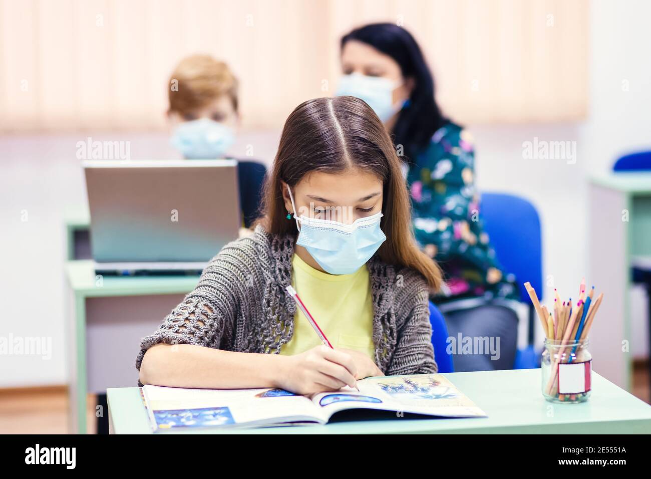 Children and teacher with face mask back to school in classroom after covid-19 lockdown Stock Photo