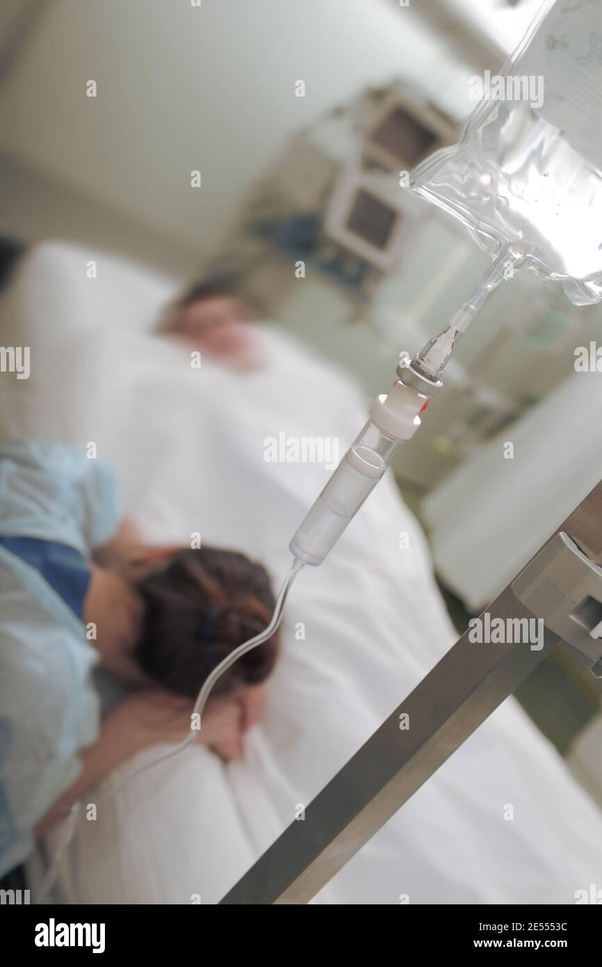 Crying woman at the man's bedside in hospital. Stock Photo