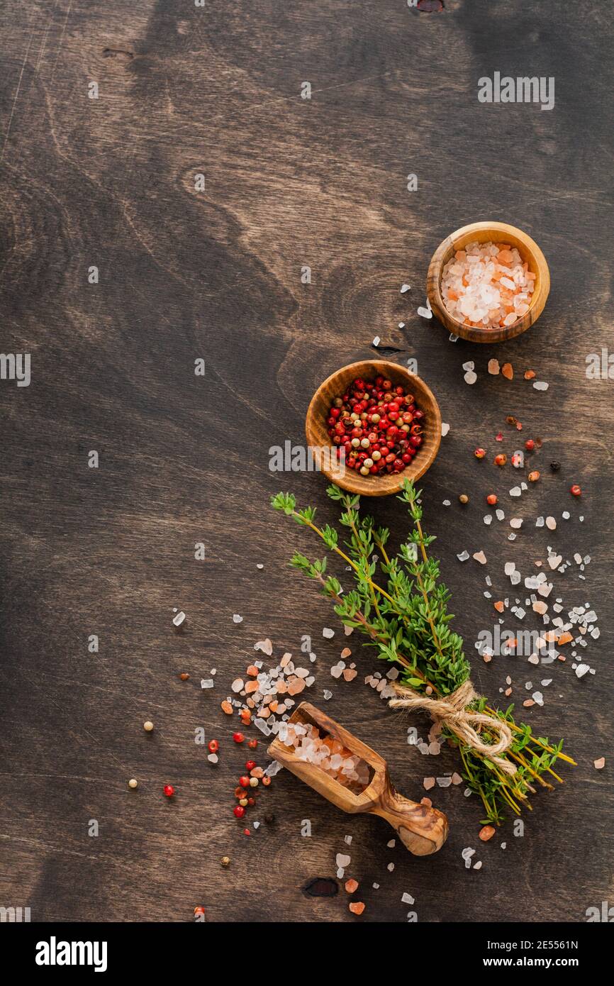 Food cooking background. Spices herbs bunch thyme and seasoning salt and pepper at black slate table. Food ingredients top view. Stock Photo
