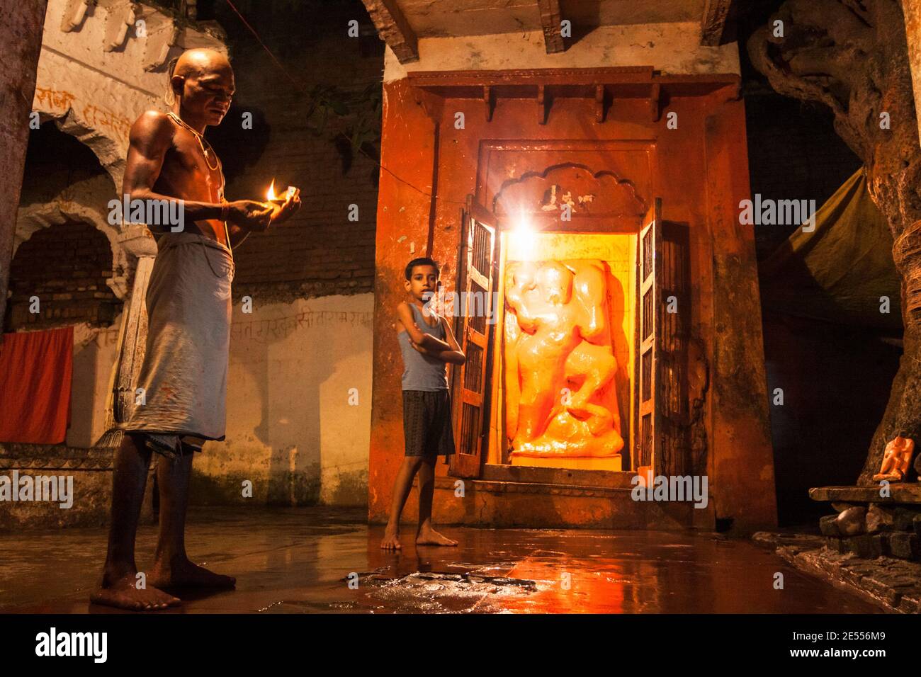 Chitrakoot, Madhya Pradesh, India : A priests holds a candle by a child inside a Hanuman shrine at night. Stock Photo