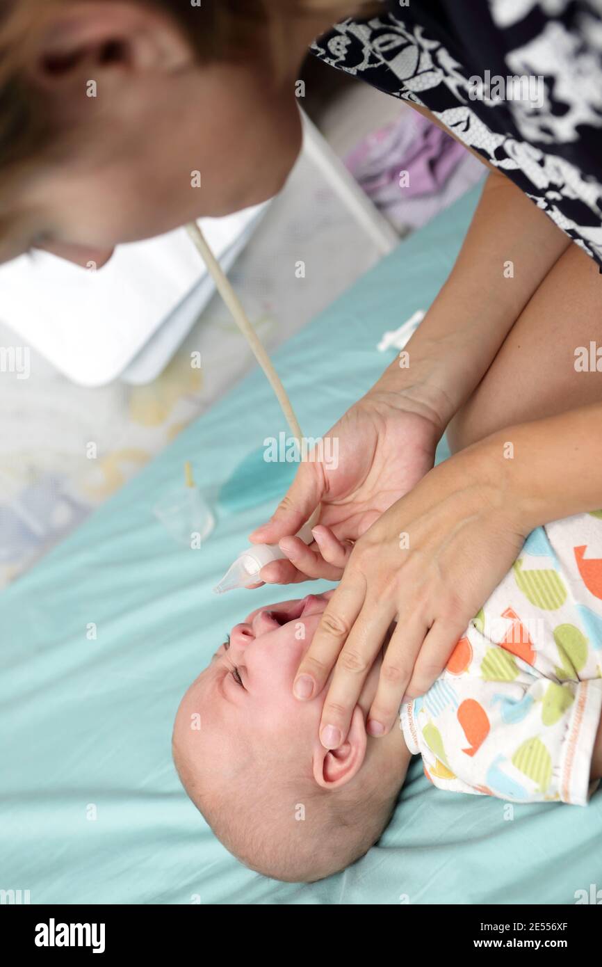 Mother using nasal aspirator for baby boy Stock Photo