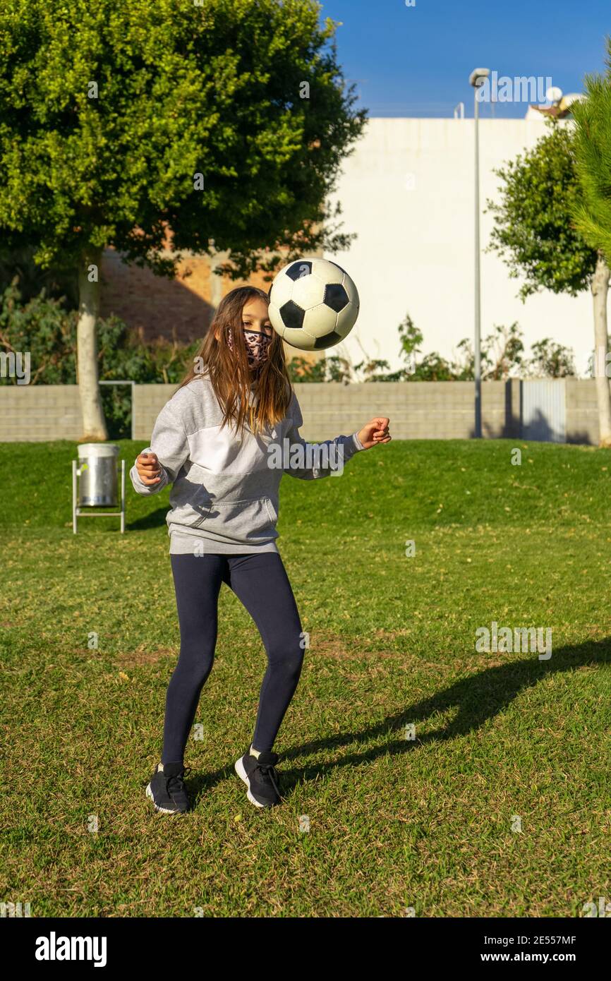 Beautiful little girl playing soccer in a nice park with natural grass ...