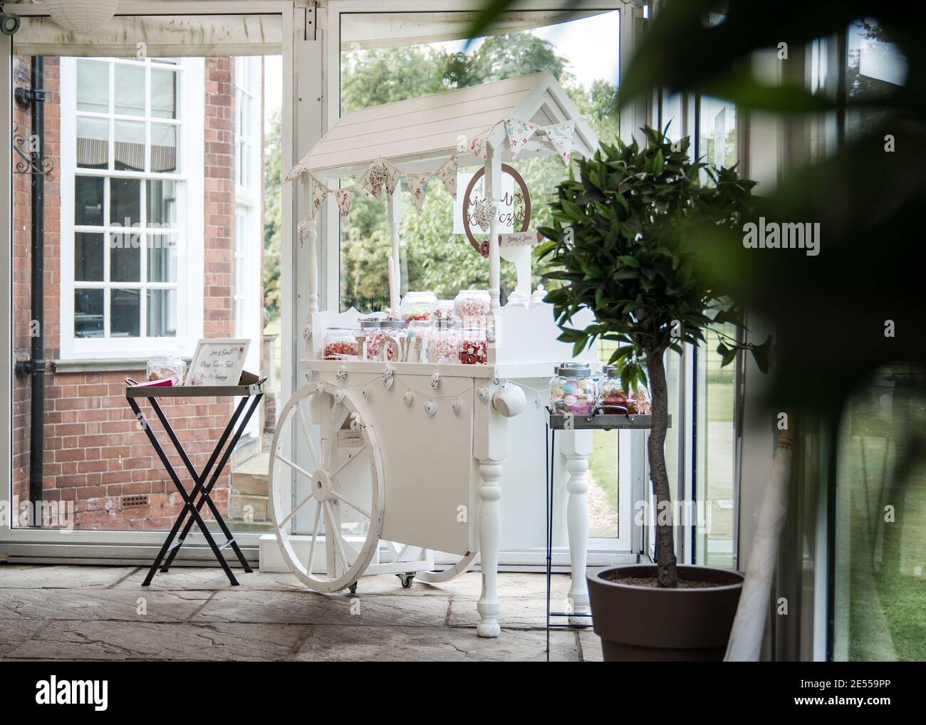 Wedding sweet trolley cart white with carriage wheels standing in venue ...