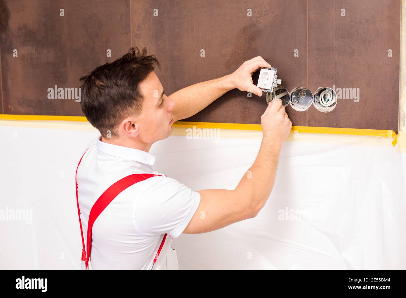 The electrician is fixing electrical wires for wall socket Stock Photo