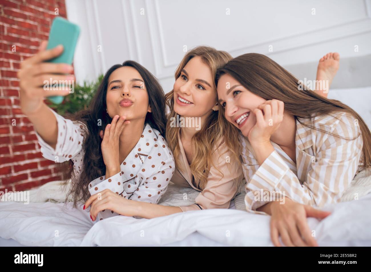 Three girls lying on bed and making selfie Stock Photo Alamy