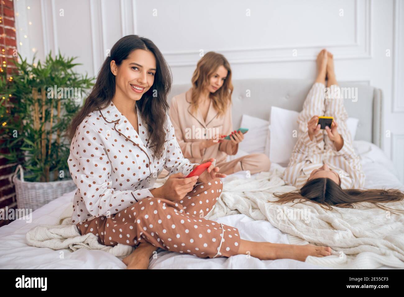 Girls with smartphones lying on bed and surfing internet Stock Photo