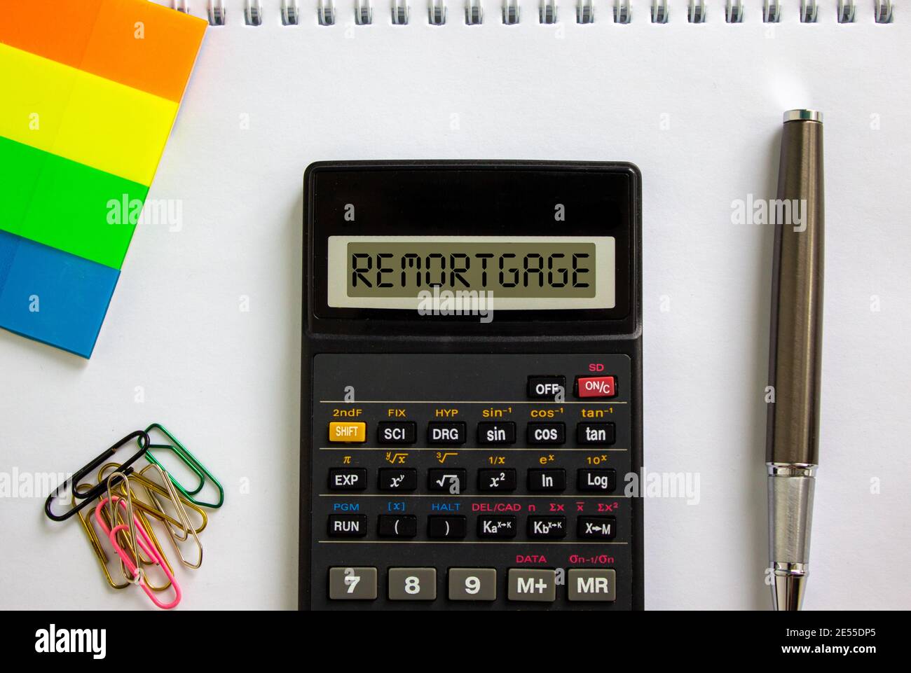 Remortgage symbol. Calculator with the word 'remortgage', white note, colored paper, paper clips, pen. Business and remortgage concept. Stock Photo