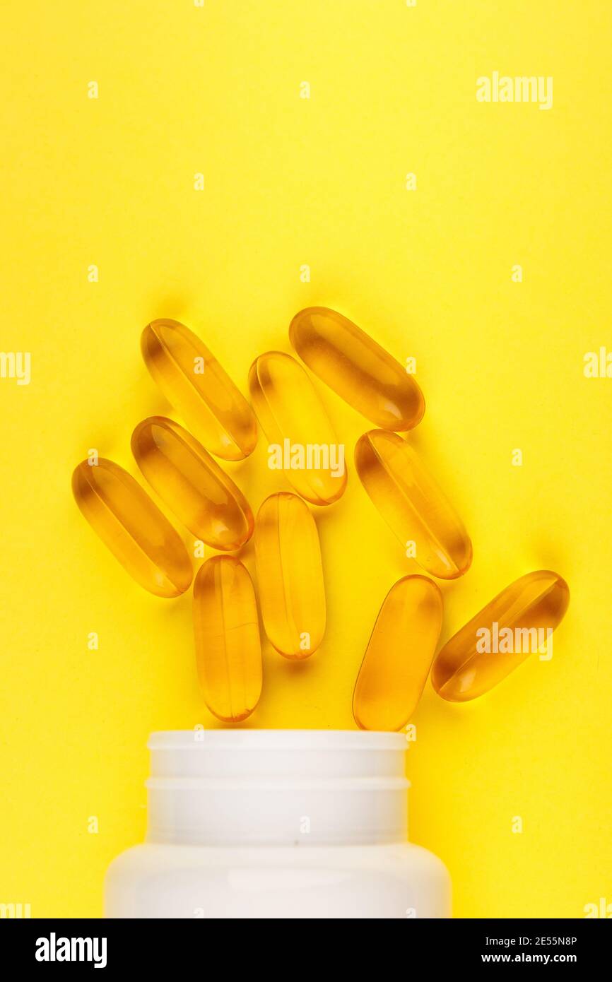 Vitamin D yellow pills on yellow and white plastic jar. Medicine gel