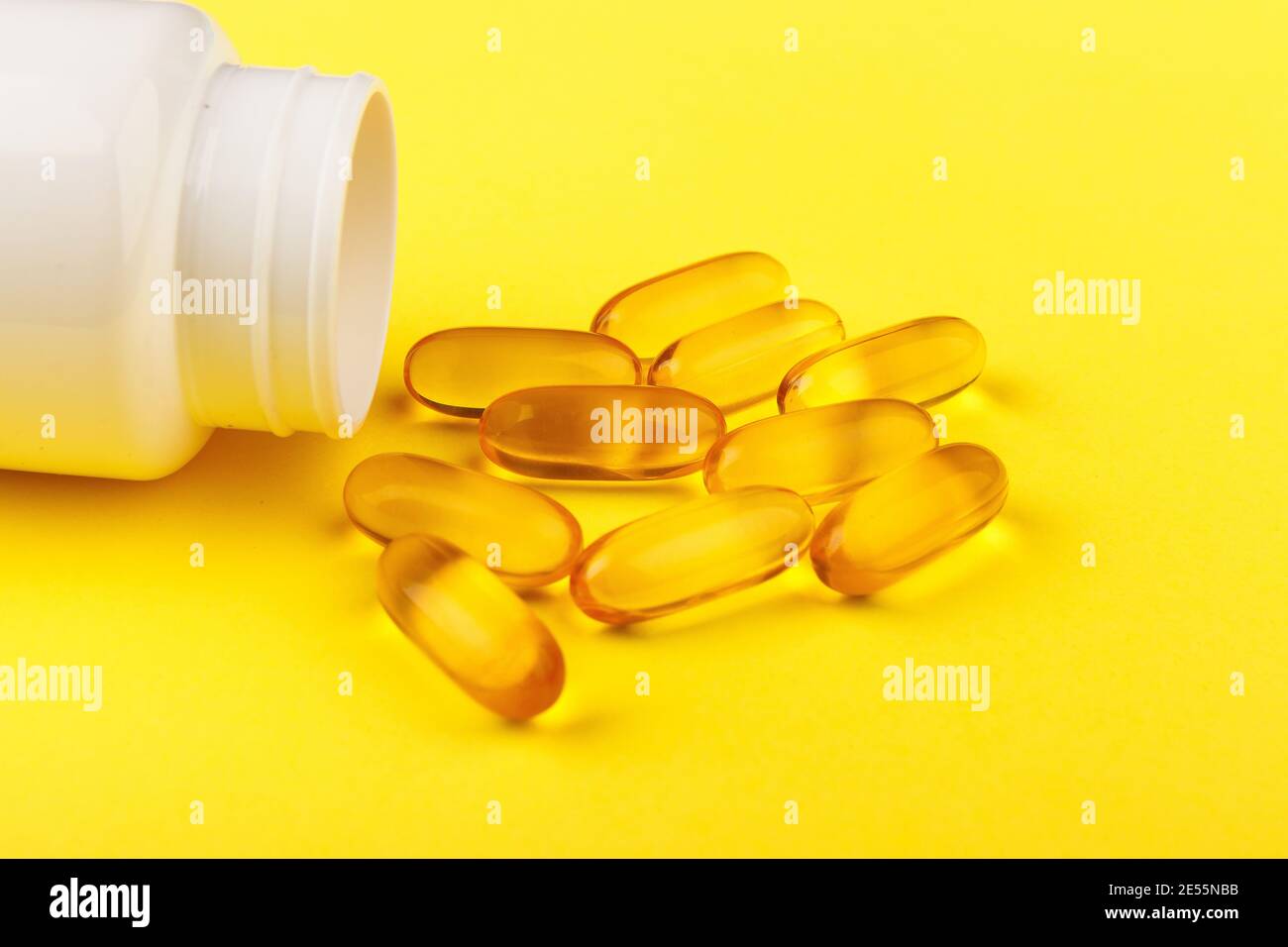 Vitamin D yellow pills on yellow background and white plastic jar