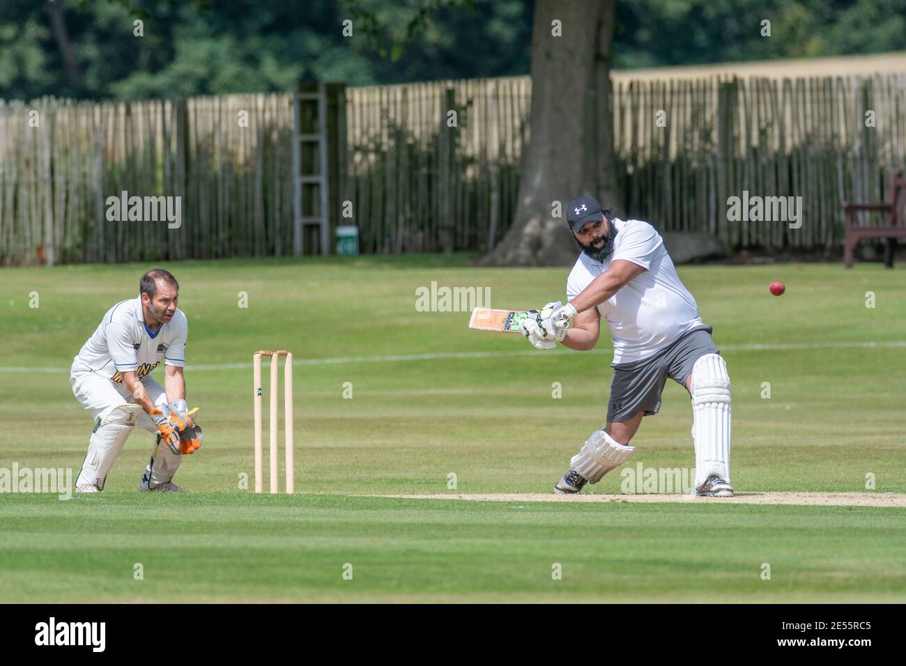 Batter prepares to swing out to hit cricket ball as wicket keeper reaches out for the catch at amateur cricket in Perth, Scotland. Stock Photo
