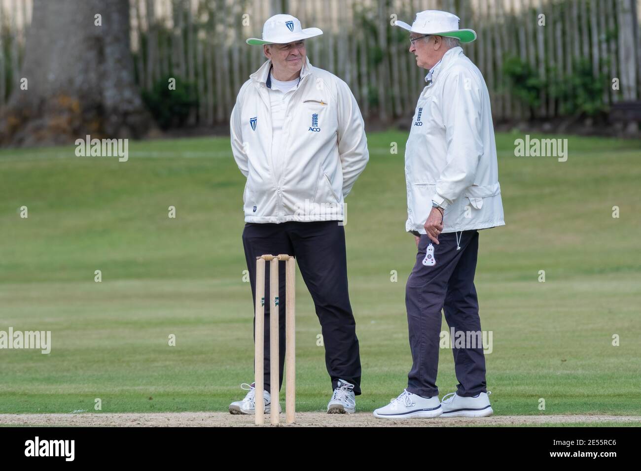 Two umpires discussing the match standing over the stumps at an amateur cricket in Perth, Scotland. Stock Photo