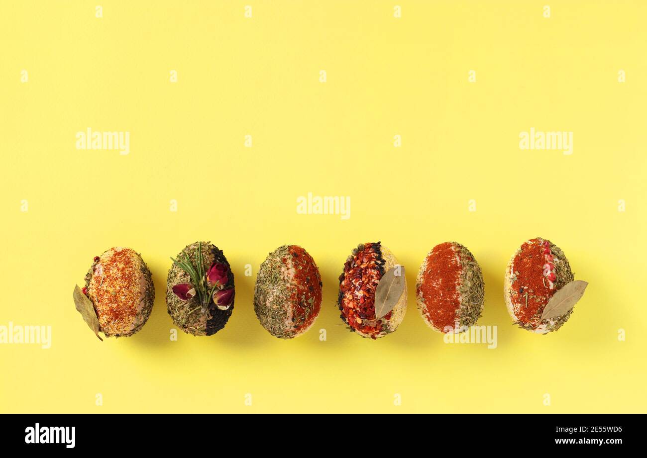 Easter concept with eggs decorated with different spices and cereals without dyes and preservatives on yellow background. Space for text Stock Photo