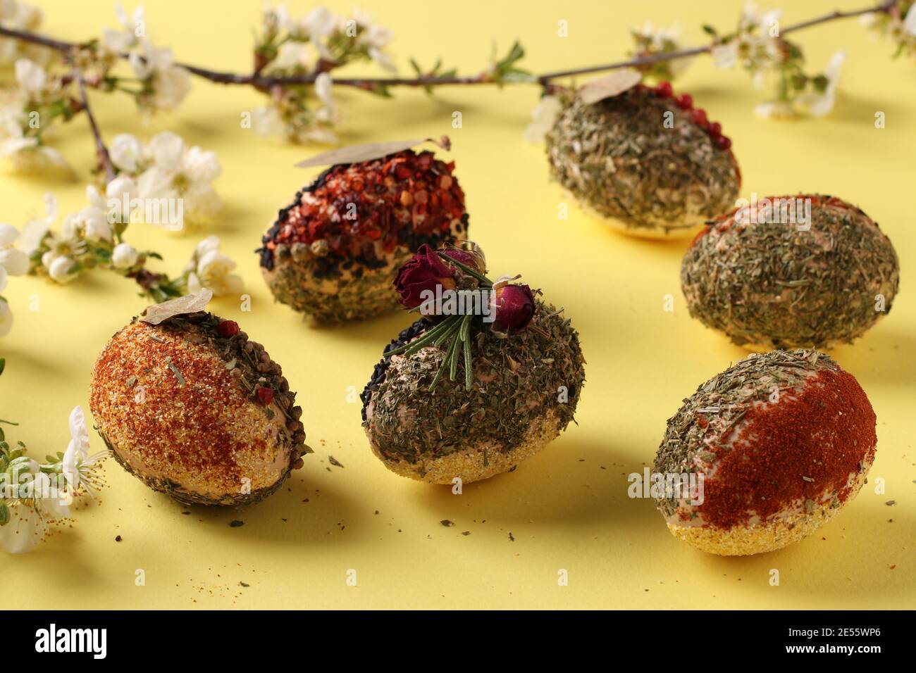 Easter concept with eggs decorated with different spices and cereals without dyes and preservatives on yellow background. Closeup Stock Photo