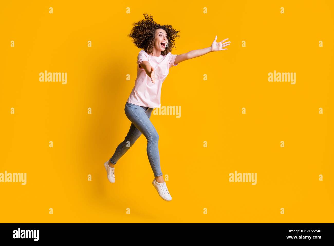 Photo portrait full body view of woman catching running jumping up isolated on vivid yellow colored background Stock Photo